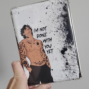 May include: A rectangular tablet case featuring a white background with black ink splatter patterns. The design displays an illustration of a shirtless person with dark hair and multiple tattoos, accompanied by the text I'M NOT DONE WITH YOU YET.