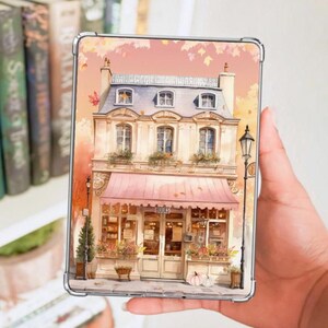 May include: A decorative case with a watercolour illustration of a charming bookstore. The image shows a pink awning with the word "BOOKS" above the entrance. The building has multiple windows with flower boxes, a street lamp, and autumn leaves.