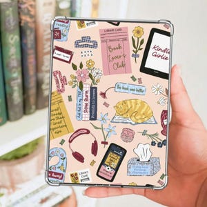 May include: A rectangular tablet case with a light pink background featuring a repeating pattern of illustrations including a sleeping orange cat, books, flowers, headphones, a tissue box, and text such as Book Lover's Club and Kindle Girlie.