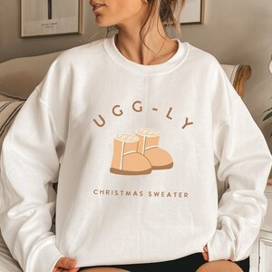 May include: White sweatshirt with a brown graphic of two Ugg boots and the text "UGG-LY CHRISTMAS SWEATER".