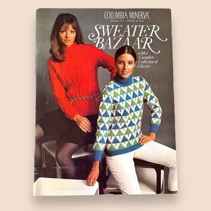 Puede incluir: Columbia Minerva Libro 771, Bazar de suéteres con una colección completa de clásicos. La portada presenta a dos mujeres con suéteres. Una mujer lleva un suéter rojo de punto de cable y una falda negra. La otra mujer lleva un suéter con estampado geométrico verde y azul y pantalones blancos.