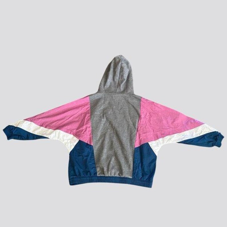 May include: A hooded sweatshirt with a color block design. The sweatshirt is gray, pink, white, and blue.