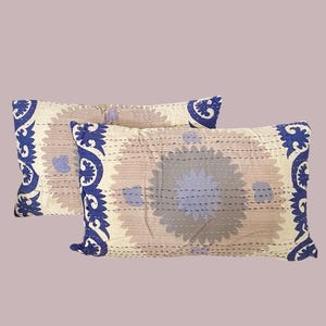May include: Two beige pillowcases with a blue floral pattern. The pillowcases have a decorative border with a paisley design.