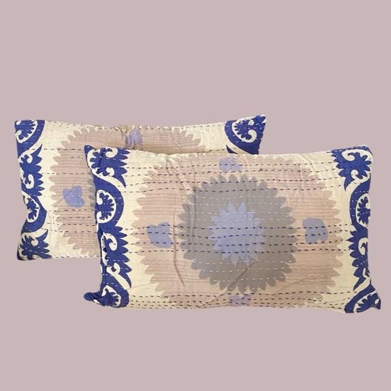 May include: Two beige pillowcases with a blue floral pattern. The pillowcases have a decorative border with a paisley design.
