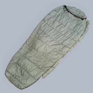 May include: A light green sleeping bag with a quilted pattern. The sleeping bag is rectangular with a rounded hood at the top. The material appears to be lightweight and suitable for outdoor use. The sleeping bag is designed to provide warmth and comfort.