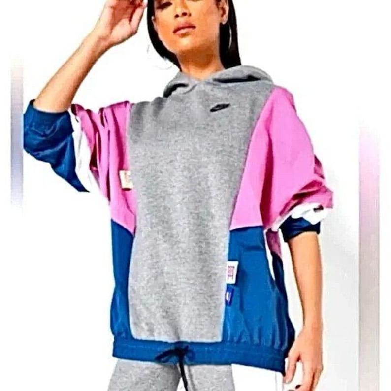 May include: A gray, pink, and blue color block hoodie with a drawstring. The hoodie has a small logo on the front.