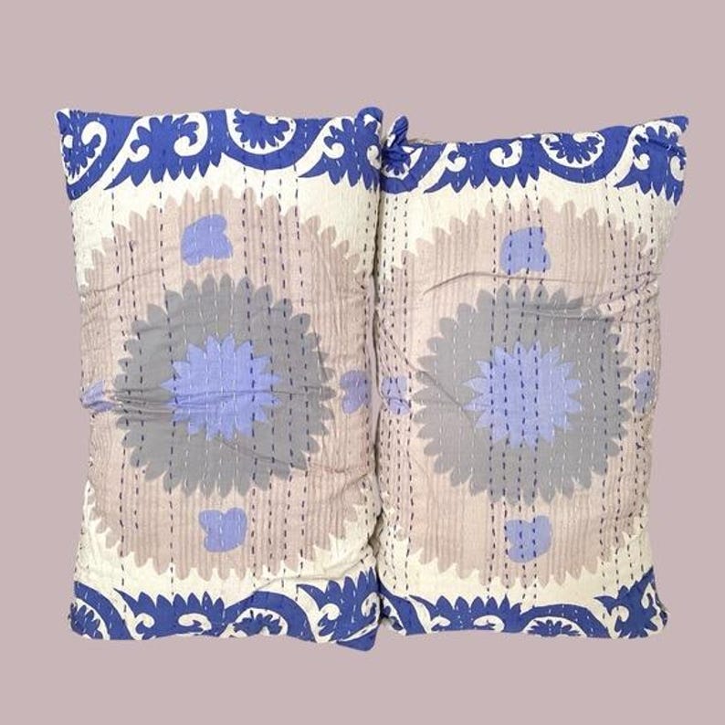 May include: Two decorative throw pillows with a floral pattern in shades of blue, gray, and white. The pillows have a blue and white border.