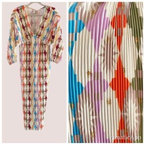 May include: A white midi dress with a geometric pattern in shades of blue, orange, pink, and green. The dress has a V-neckline and 3/4 sleeves.