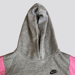 May include: Gray hooded sweatshirt with pink accents and a black Nike logo on the front.