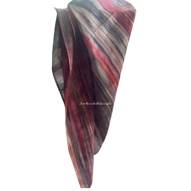 May include: A lightweight silk scarf featuring a vertical abstract pattern in shades of deep red, burgundy, grey, and black. The fabric has a semi-sheer quality with visible folds and the text "Jim Rose Silk Scarfs" printed in white in the centre.