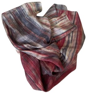 May include: A lightweight scarf featuring a vertical striped pattern in shades of deep red, charcoal grey, and cream. The fabric displays a soft, flowing texture with the text "Jim Rose Silk Scarfs" printed in white in the centre of the material.