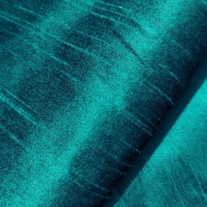 May include: Close-up of a teal fabric with a smooth, silky texture. The fabric is folded in half, showing the sheen of the material.