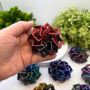 Pode incluir: Um conjunto de objetos geom&eacute;tricos quadrados em v&aacute;rias cores, incluindo vermelho, preto, azul e verde. Os objetos est&atilde;o dispostos em forma esf&eacute;rica. Outros objetos semelhantes s&atilde;o vis&iacute;veis no fundo.
