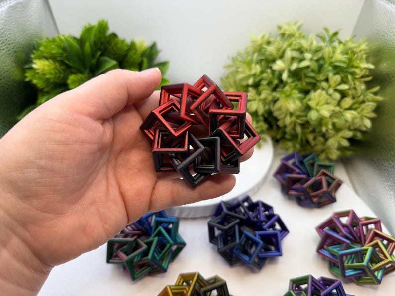 Pode incluir: Um conjunto de objetos geom&eacute;tricos quadrados em v&aacute;rias cores, incluindo vermelho, preto, azul e verde. Os objetos est&atilde;o dispostos em forma esf&eacute;rica. Outros objetos semelhantes s&atilde;o vis&iacute;veis no fundo.