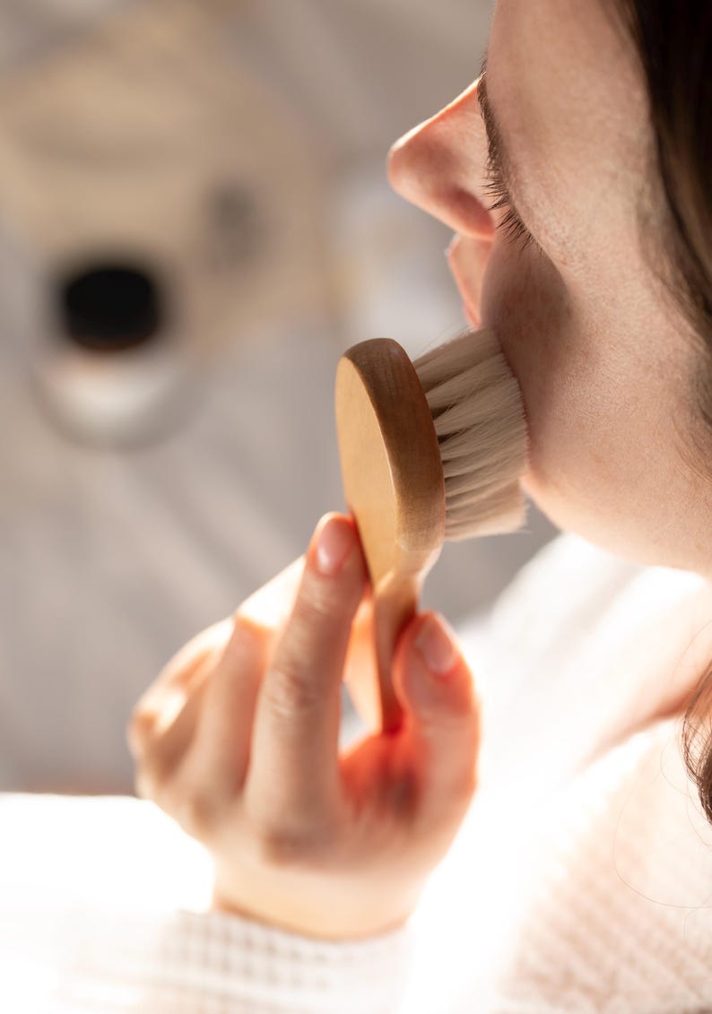 Facial dry brushing with Kayle at Home brush, gently gliding over the skin to encourage blood flow and enhance skincare absorption.
