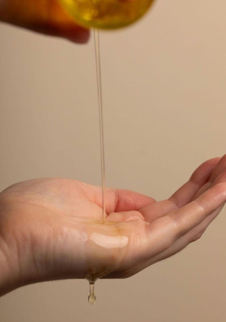 May include: A hand with a clear liquid dripping onto it from above.