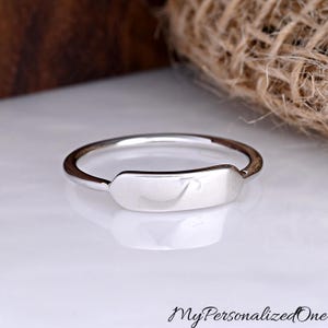 May include: A polished silver ring featuring a smooth, rectangular bar centerpiece with rounded edges. The band is thin and circular, reflecting light on its metallic surface. The text MyPersonalizedOne is visible in the bottom right corner.