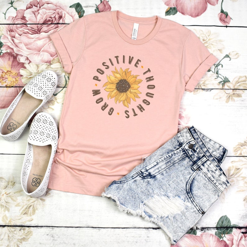 May include: A pink t-shirt with a sunflower graphic and the text "Grow Your Positive Thoughts".