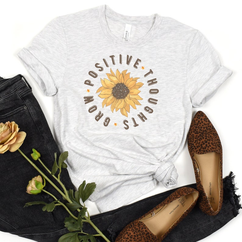 May include: A grey t-shirt with a sunflower graphic and the text "Grow Positive Thoughts".