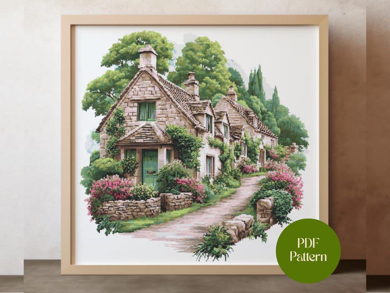 May include: A framed watercolor print of a quaint village scene. Stone cottages with green doors and windows are surrounded by lush greenery and pink flowers. A cobblestone path leads through the village. The print is in a light wood frame.