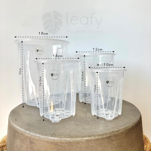May include: Four clear plastic plant pots of different sizes. The pots are labelled "leafy the leafy brand". The pots are 18 cm, 14 cm, 12 cm, and 10 cm in diameter.