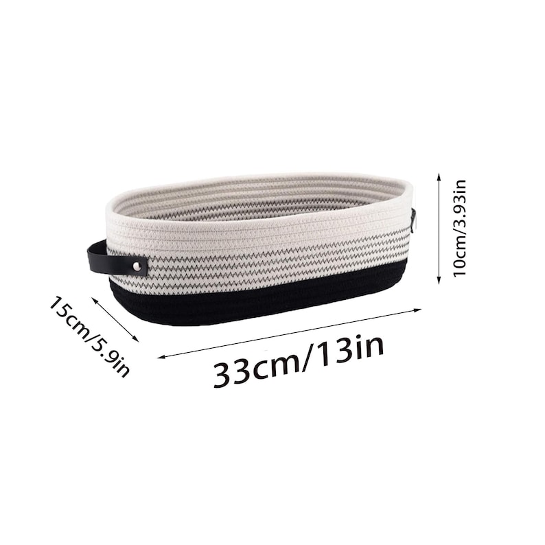 Op de afbeelding: Een wit-zwarte gestreepte opbergmand van katoenen touw met zwarte leren handvatten. De mand is 33 cm lang, 15 cm breed en 10 cm hoog.