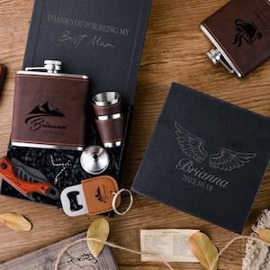 May include: A gift set for a best man, featuring a brown leather flask with a mountain design and the name Brianna engraved on it, a small brown leather shot glass, a bottle opener, a small knife, and a funnel. The set is packaged in a black box with the words "Thank you for being my Best Man" on the lid.