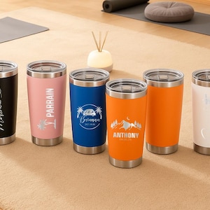 May include: A collection of six stainless steel insulated tumblers with silver lids. The tumblers are in various colors, including black, pink, blue, and orange. Each tumbler has custom text or graphics, such as names and dates, making them personalized gifts.