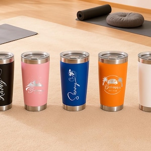 May include: Five stainless steel insulated tumblers in black, pink, blue, orange, and white. Each tumbler has a silver lid and base. The black tumbler has the name "Kathy" in a cursive font. The other tumblers have custom designs and names.