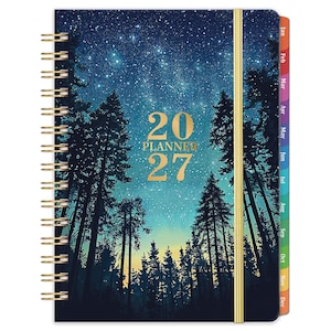 May include: A 2027 planner with a spiral binding and a gold elastic closure. The cover features a dark blue night sky filled with stars above a silhouette of pine trees. The text 20 PLANNER 27 is printed in gold in the centre. Includes monthly tabs.