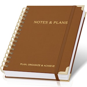 May include: A brown spiral-bound notebook with gold lettering that reads "NOTES & PLANS" and "PLAN, ORGANIZE & ACHIEVE." The notebook has a brown elastic band and gold corner protectors.