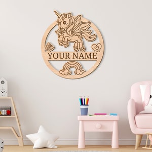 May include: A wooden round sign with a unicorn, rainbow, and clouds design. The sign has a space for a name, and the text "YOUR NAME" is visible.