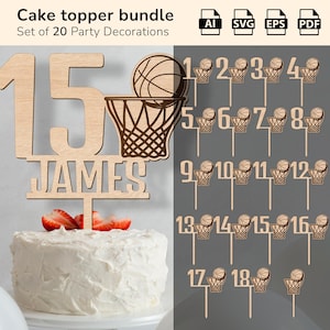 Puede incluir: Un conjunto de adornos para tartas de madera con temática de baloncesto. El conjunto incluye un adorno grande con el número "15" con el nombre "JAMES", un diseño de baloncesto y aro, y adornos individuales numerados del 1 al 18. La tarta está cubierta con fresas.
