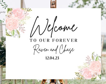 May include: White wedding welcome sign with pink floral accents. The sign reads "Welcome to our forever Raven and Chase 12.04.23".