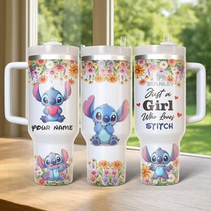 Pu&ograve; includere: Tre bicchieri isolati bianchi con disegni floreali e immagini di Stitch. Un bicchiere dice "Your Name", un altro presenta Stitch che tiene un cuore, e il terzo dice "Just a Girl Who Loves Stitch". Ogni bicchiere ha un manico bianco.
