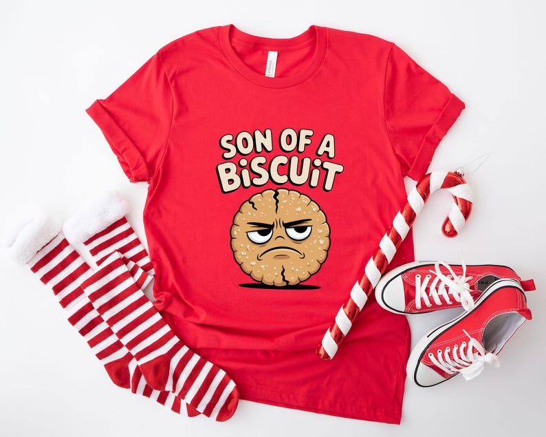 May include: A red t-shirt with the text "SON OF A BISCUIT" and a cartoon biscuit character. The image also includes red and white striped socks, a candy cane, and red sneakers.