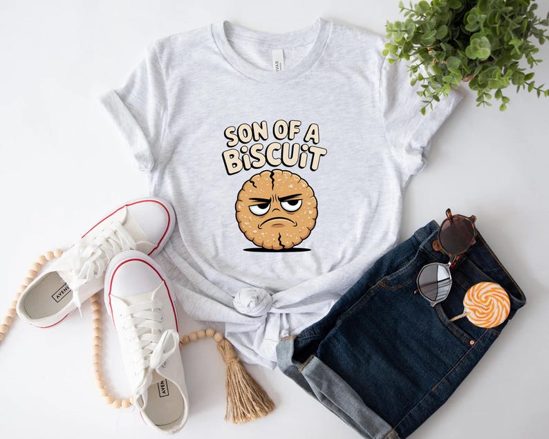 May include: A light gray t-shirt with the text "SON OF A BISCUIT" above a cartoon biscuit with an angry face. White sneakers with red trim, sunglasses, and a lollipop are also visible.