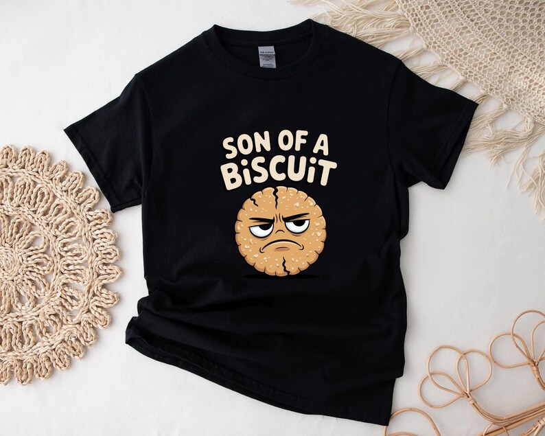 May include: Black t-shirt with the text "SON OF A BISCUIT" above a cartoon biscuit with an angry face. The biscuit is light brown with a darker brown outline and details.