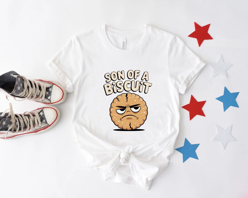 May include: White t-shirt with the phrase "SON OF A BISCUIT" and a cartoon biscuit with an angry face. The shirt is paired with high-top sneakers and star-shaped decorations in red, white, and blue.