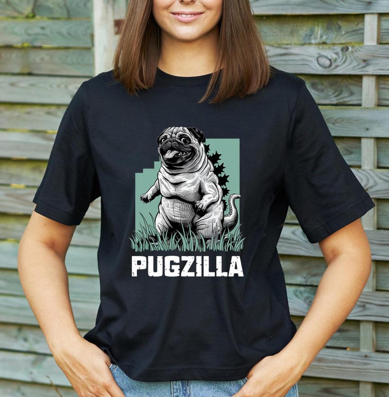 May include: Black t-shirt with a graphic of a pugzilla, a pug with a Godzilla-like pose, on a green background. The text "PUGZILLA" is printed below the graphic.