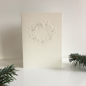 Handgemachte Weihnachtskarte mit Schneeflockenkranz und Glitzersteinchen