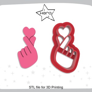 May include: Two 3D printed cookie cutters in the shape of a hand making a heart sign. The cutter on the left is pink and the cutter on the right is red.