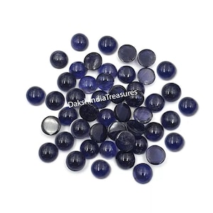 Puede incluir: Una colección de piedras preciosas redondas de cabujón azul oscuro. Las piedras preciosas son lisas y pulidas, con un ligero brillo. Las piedras preciosas tienen un diámetro aproximado de 10 mm.