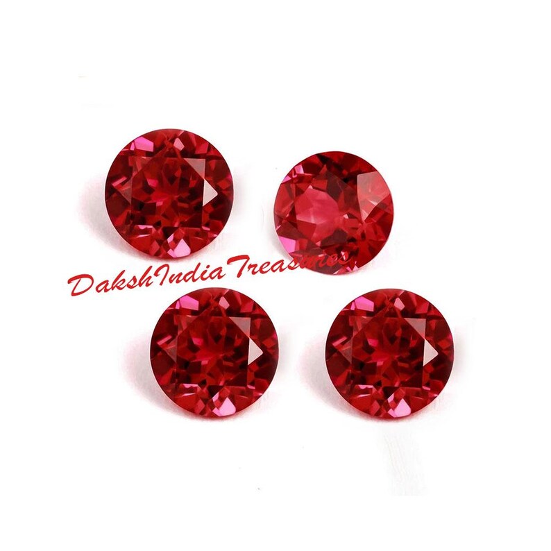 K&ouml;nnte beinhalten: Vier runde, facettierte, tiefrote Edelsteine. Die Edelsteine sind in einem quadratischen Muster auf wei&szlig;em Hintergrund angeordnet. Der Text "Daksh India Treasures" befindet sich in der unteren linken Ecke.