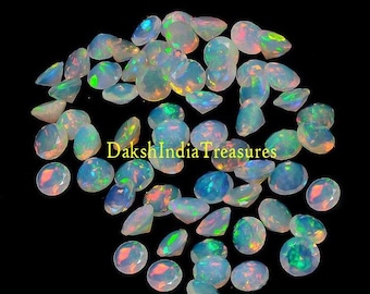 May include: A collection of iridescent opal gemstones in various shades of white, blue, and green. The gemstones are round and have a smooth, polished finish.  The text "DakshIndiaTreasures" is visible in the image.