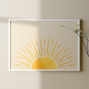 以下が含まれることがあります： ベージュの壁に、黄色い太陽とそこから放射状に伸びる光線が描かれた額装されたプリントが飾られています。プリントの下のウッドテーブルには、緑の葉の枝が入った花瓶が置かれています。