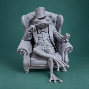 May include: A monochromatic gray figurine of a frog sitting in a tufted wingback chair. The frog wears a top hat, a bow tie, a button-down shirt, a jacket, and shorts. It holds a smoking pipe in one hand and rests the other near its chin.