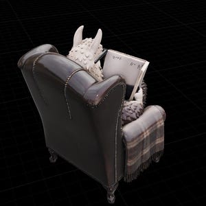 May include: A detailed sculpture of a creature with horns and textured fur, reading a book while seated in a dark brown leather armchair. A plaid blanket is draped over the chair. The book has Japanese text.