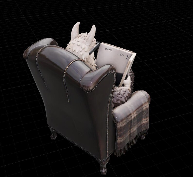 May include: A detailed sculpture of a creature with horns and textured fur, reading a book while seated in a dark brown leather armchair. A plaid blanket is draped over the chair. The book has Japanese text.