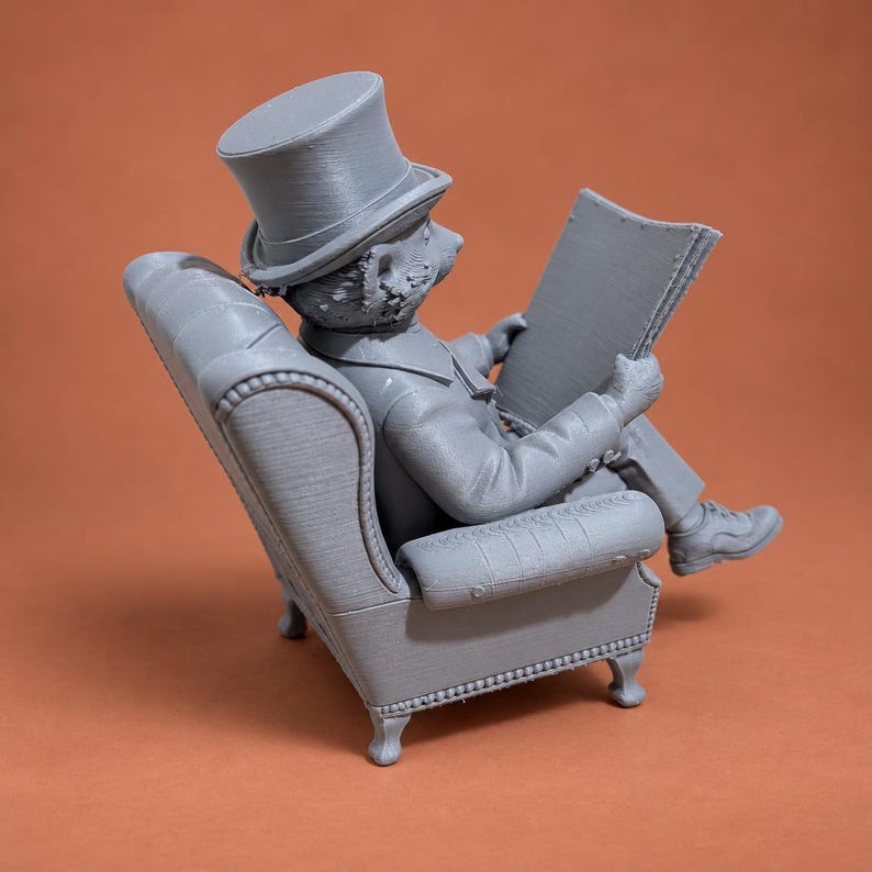 May include: A gray 3D printed figurine of an anthropomorphic bear wearing a top hat and formal attire, seated in a tufted armchair while holding an open newspaper. The bear is depicted in profile, showing detailed textures on the chair and clothing.